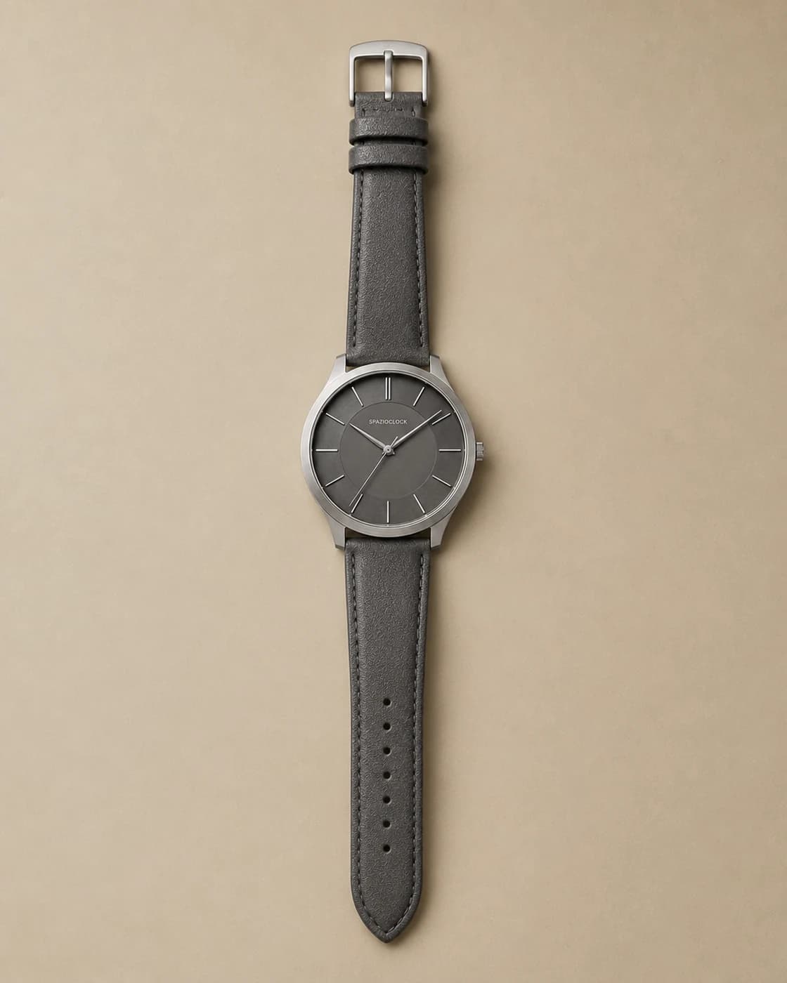 Meridiano Ombra de Spazioclock, reloj en gris humo fotografiado sobre fondo piedra